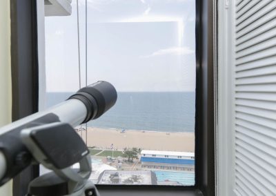 A telescope looking out of the window at the beach.