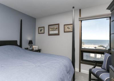 A bedroom with a view of the ocean and beach.