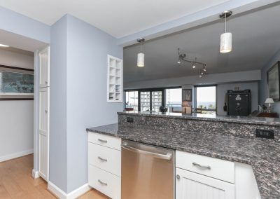 A kitchen with white cabinets and granite counter tops.