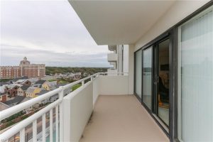 A balcony with sliding glass doors and a view of the ocean.