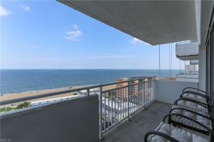 A balcony with chairs and a view of the ocean.