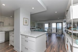 A kitchen with white cabinets and wooden floors.