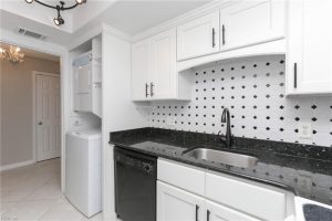 A kitchen with white cabinets and black counter tops.