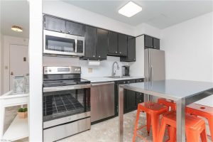 A kitchen with stainless steel appliances and orange stools.