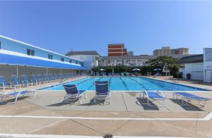 A pool with chairs and umbrellas in the background.