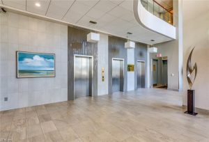 A lobby with three elevators and a painting on the wall.