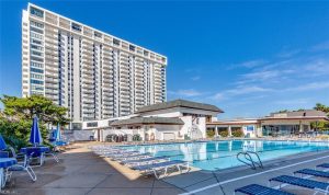 A pool with chairs and a building in the background.