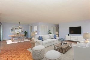 A living room with white furniture and a large flat screen tv.