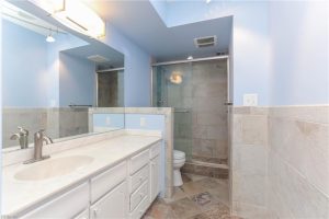 A bathroom with blue walls and white cabinets.