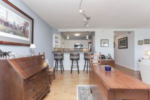 A living room with a table and chairs, a bar and a kitchen.