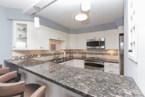 A kitchen with white cabinets and granite counter tops.