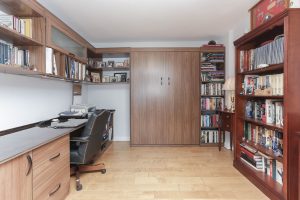 A room with a desk and bookcase in it