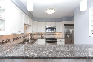 A kitchen with granite counter tops and white cabinets.