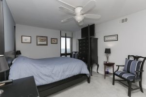 A bedroom with a bed, dresser and chair.