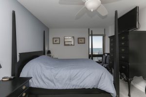 A bedroom with a bed, dresser and window.