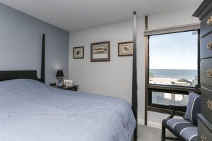 A bedroom with a view of the ocean and beach.