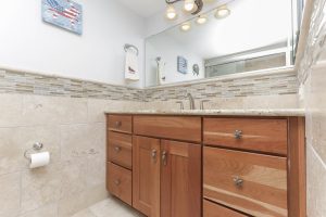 A bathroom with a sink, mirror and wooden cabinets.