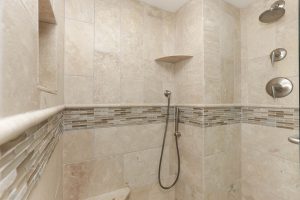 A bathroom with beige tile and a shower.