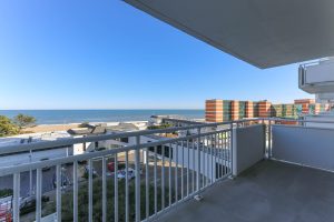 A balcony with a view of the ocean and buildings.