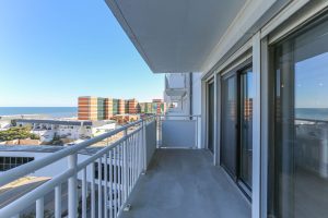 A balcony with a view of the ocean and buildings.