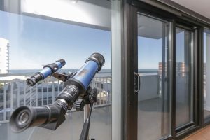 A telescope is on the balcony of an apartment.