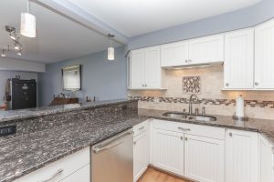 A kitchen with white cabinets and granite counter tops.